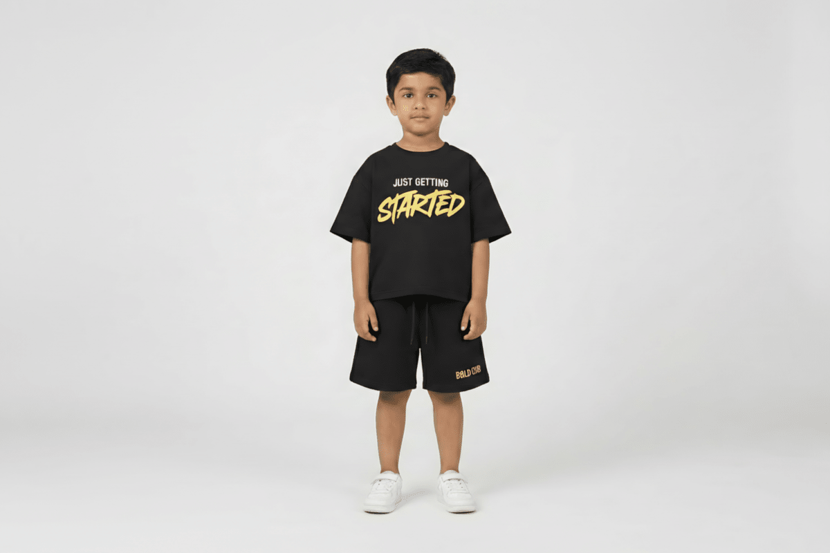 Child wearing a black t-shirt with 'Just Getting Started' text and black shorts on a white background