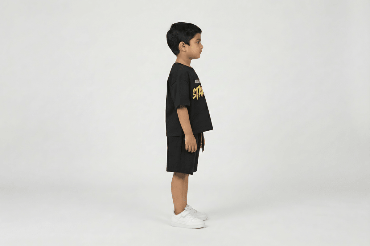 Child wearing a black t-shirt with yellow text and shorts on a white background