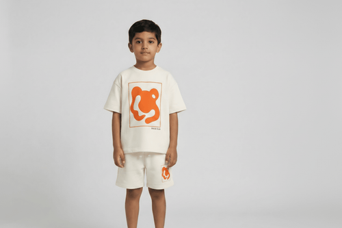 Child wearing a white t-shirt and shorts with an orange logo on a plain background