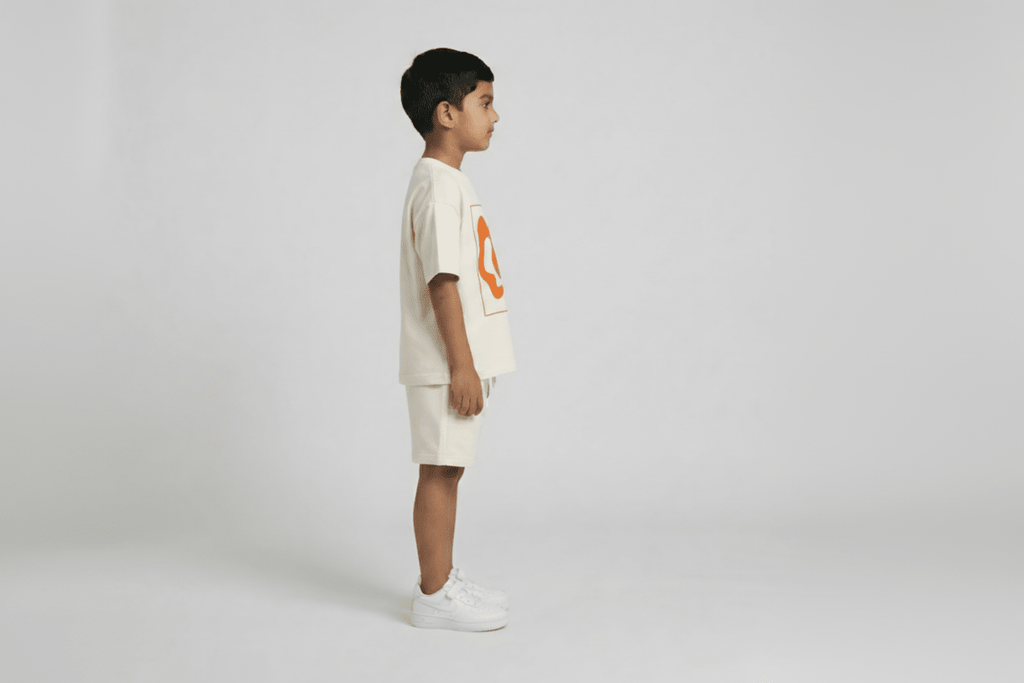 Child wearing a beige t-shirt with an orange logo and shorts on a white background