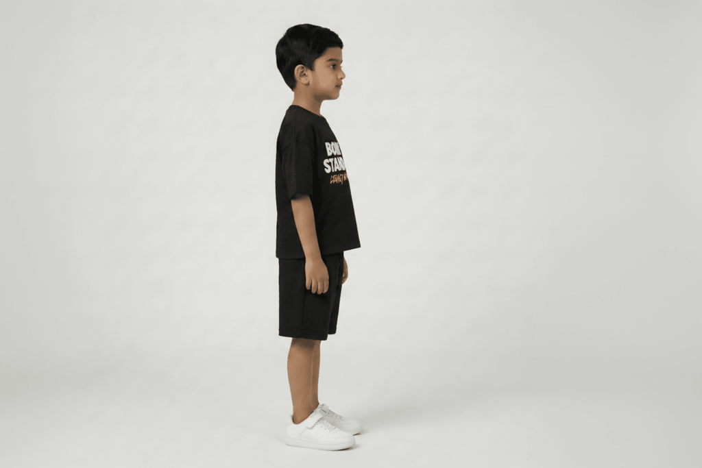 Child wearing a black t-shirt and shorts with visible branding on a white background
